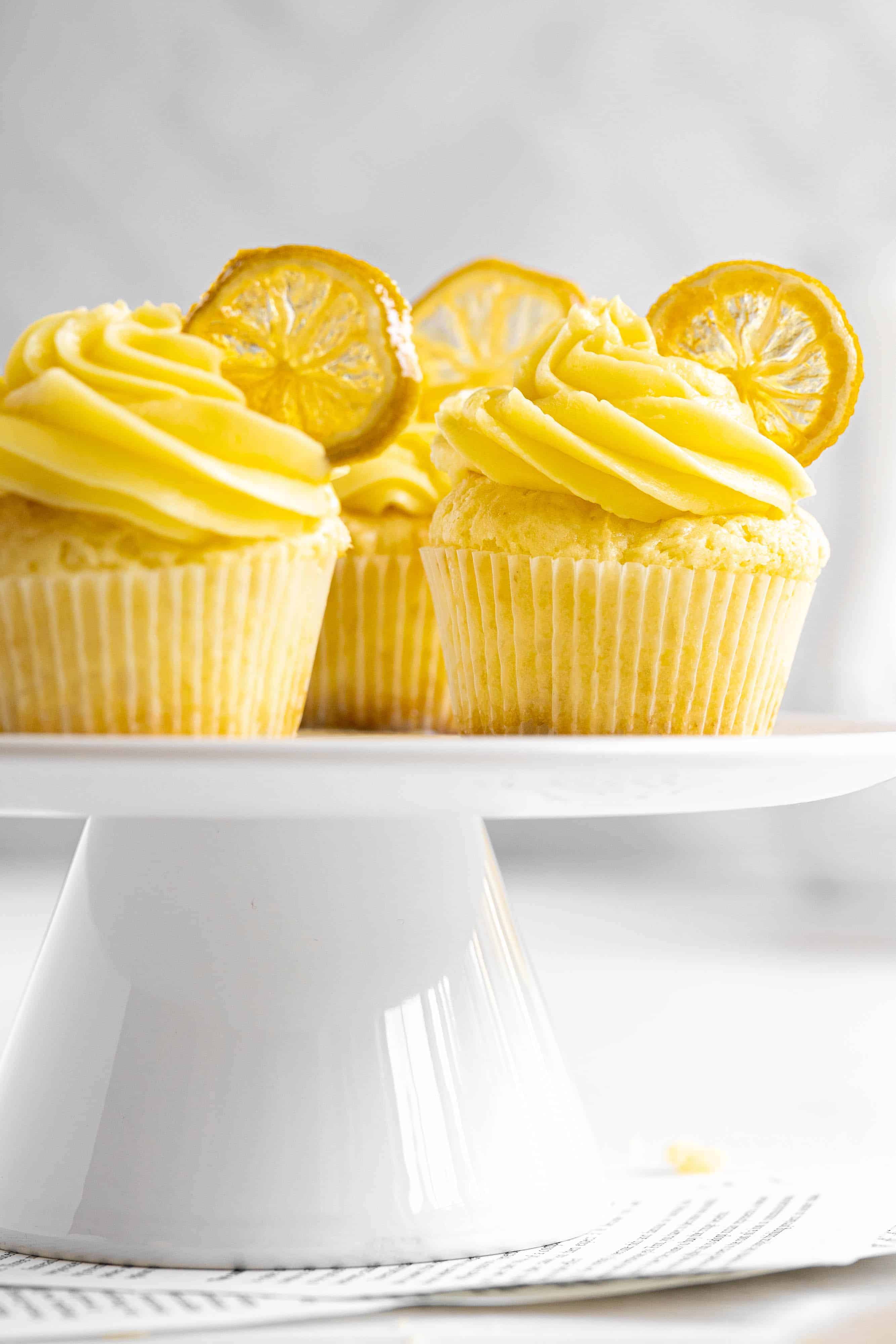 A white table with lemon cupcakes with candied lemon slices