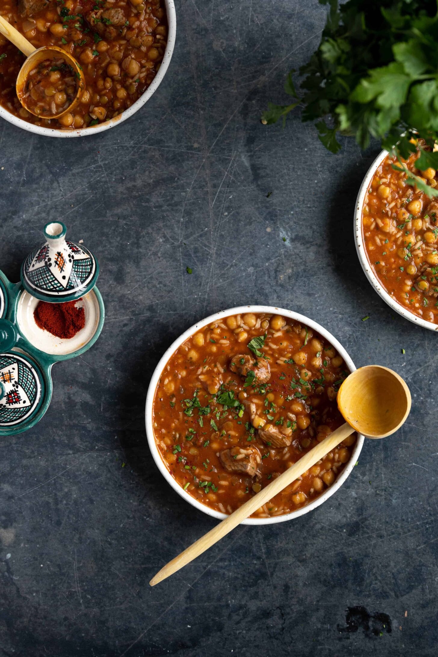 Three bowls of Moroccan soup on a black table
