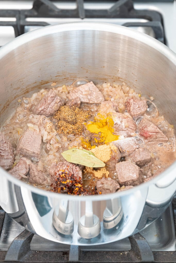 a pot with lamb, onions and spices sautéing