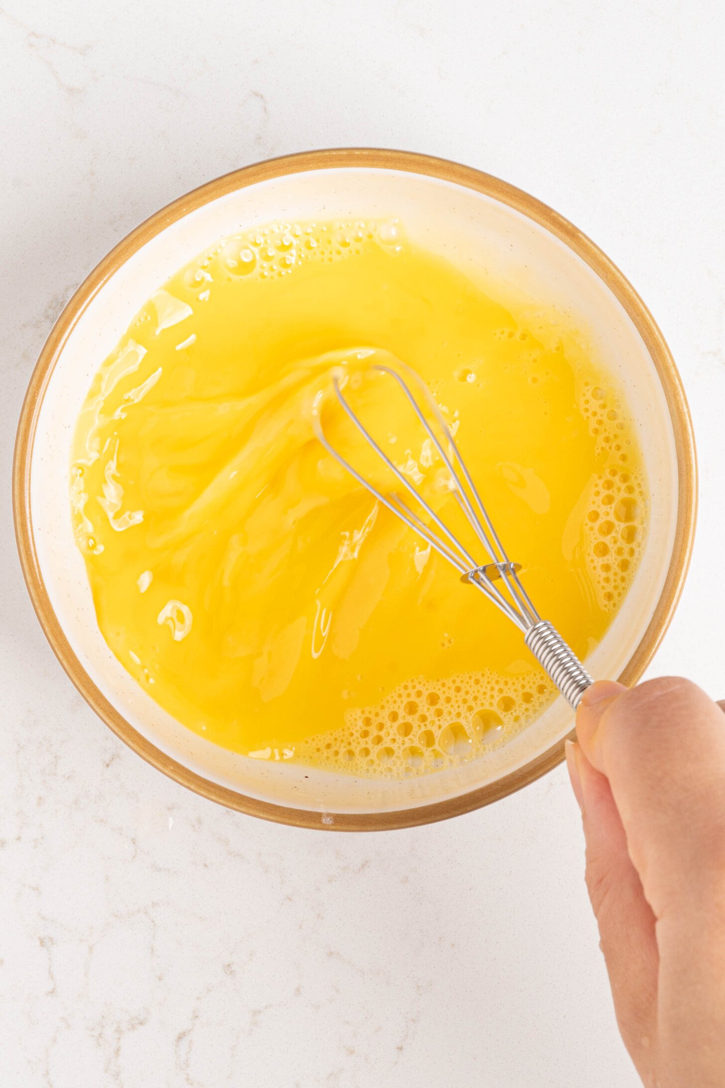 Egg being beaten in a bowl.