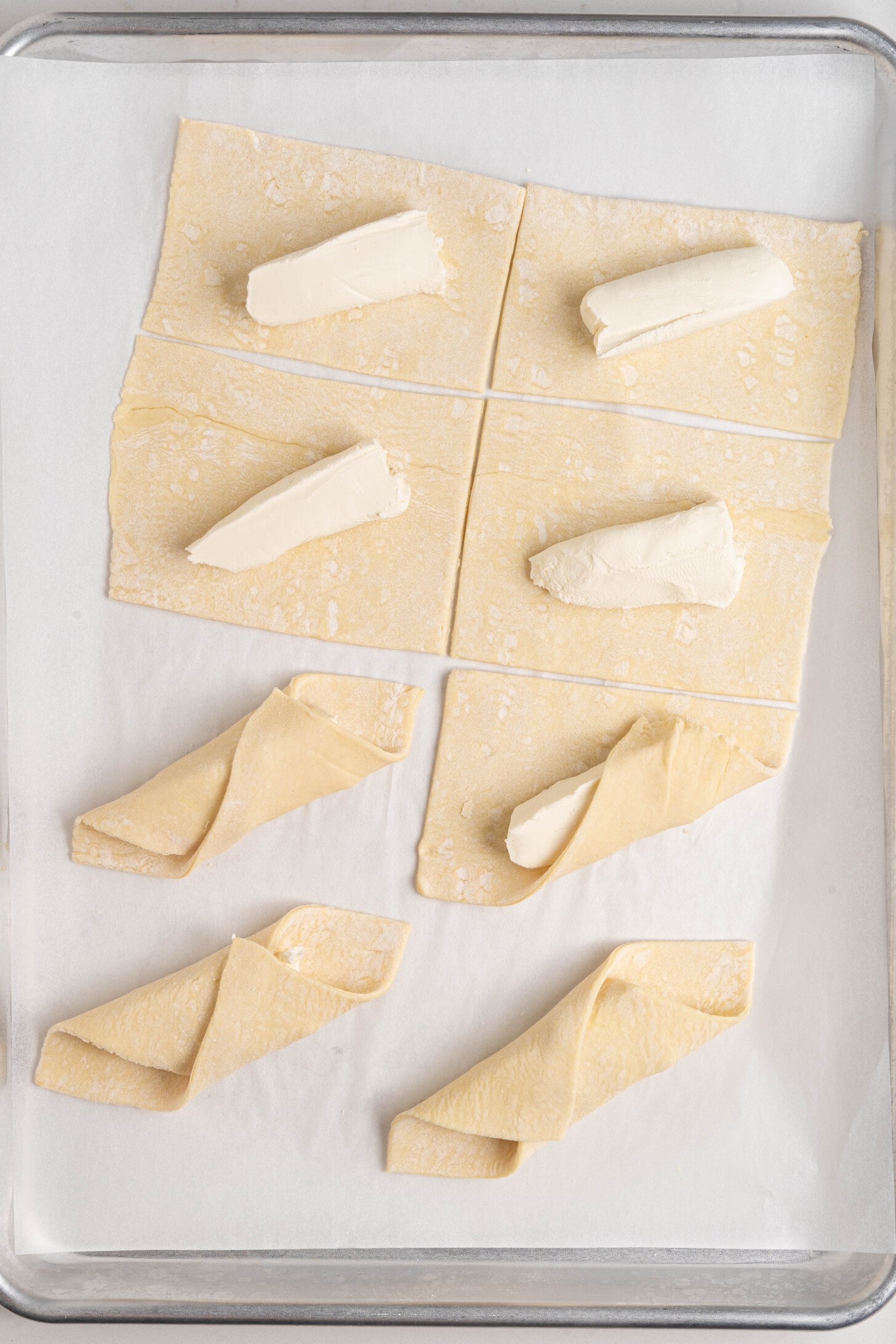 Puff pastry and cream cheese being folded together.