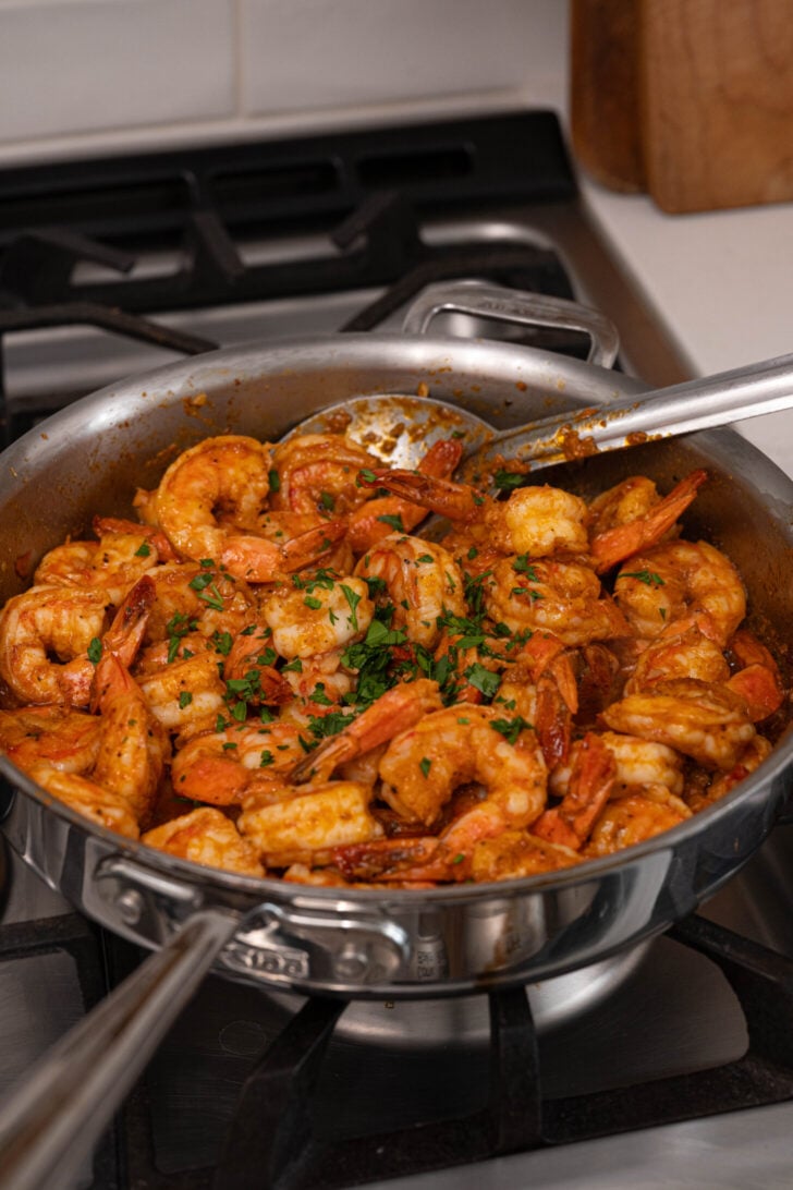 A pan with garlic butter shrimp and parsley.