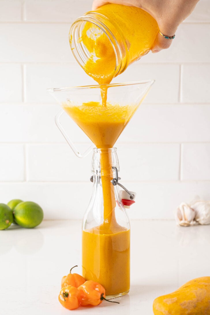 The hot sauce is pouring into a bottle.