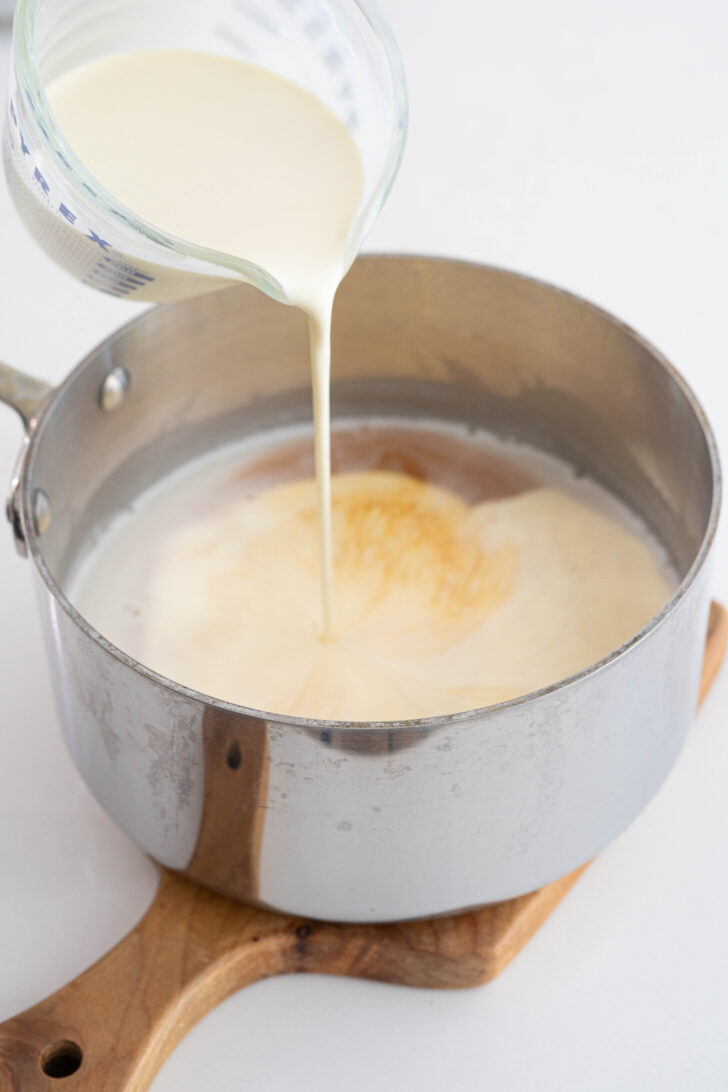 Heavy cream is pouring into a coconut milk vessel.