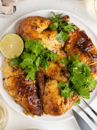 A cut whole roasted chicken on a plate.