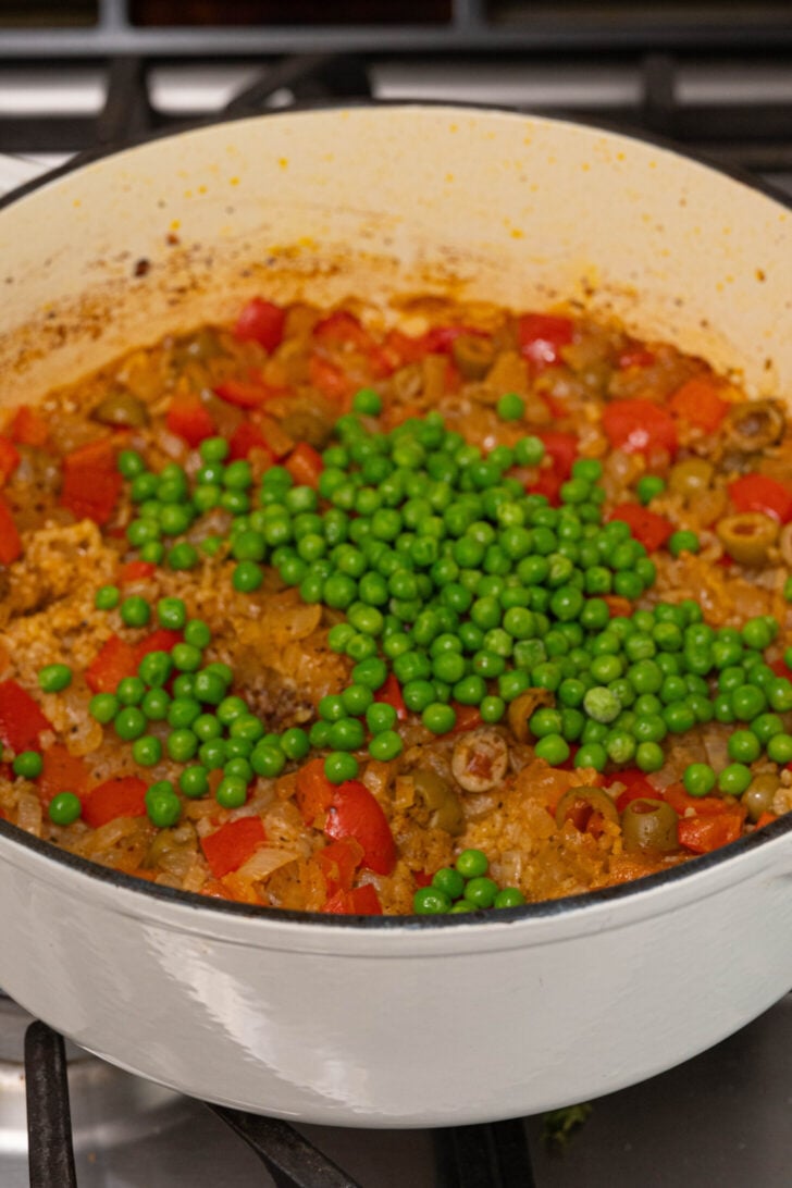 Peas on top of a pot of arroz con pollo.