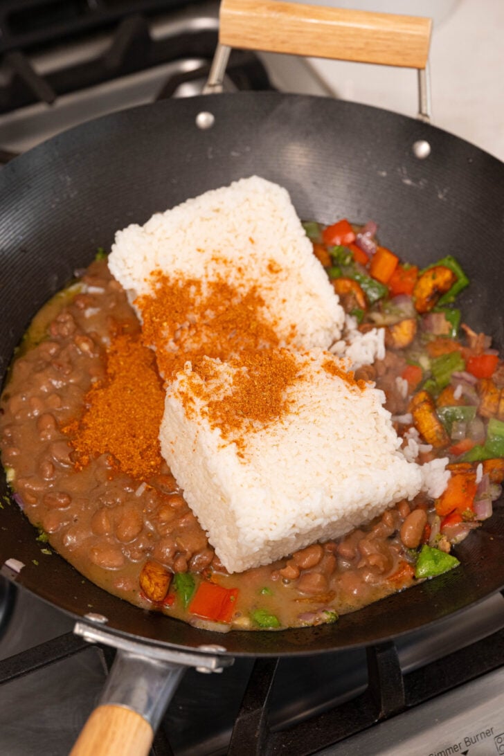 Rice, beans and vegetables frying in a wok.