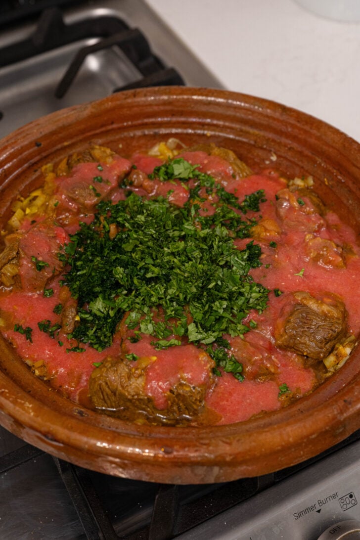 A tagine with beef, tomato sauce, and herbs.