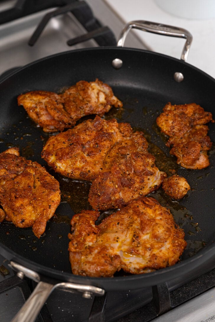 Sazon seasoned chicken frying in a pan.
