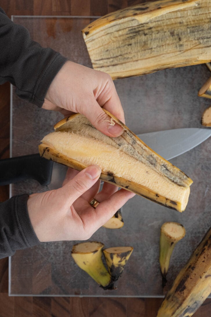 Hands peeling a brown plantain.