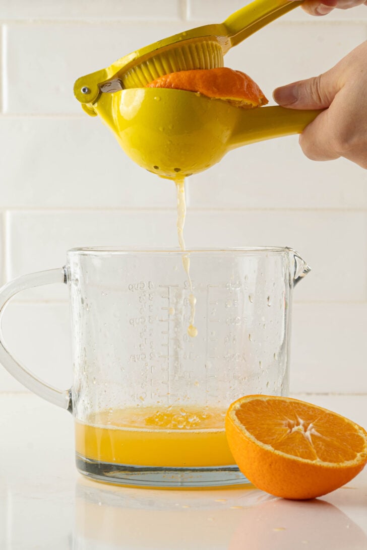 Oranges squeezing into a pitcher.