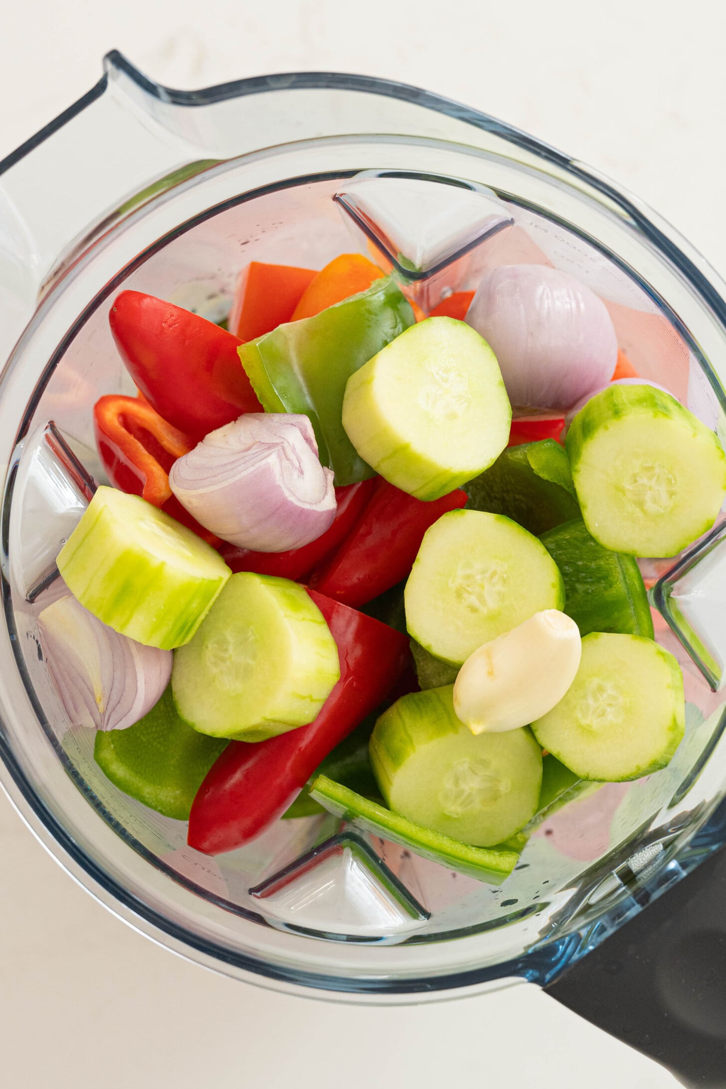 A blender with tomatoes, cucumbers, and more.