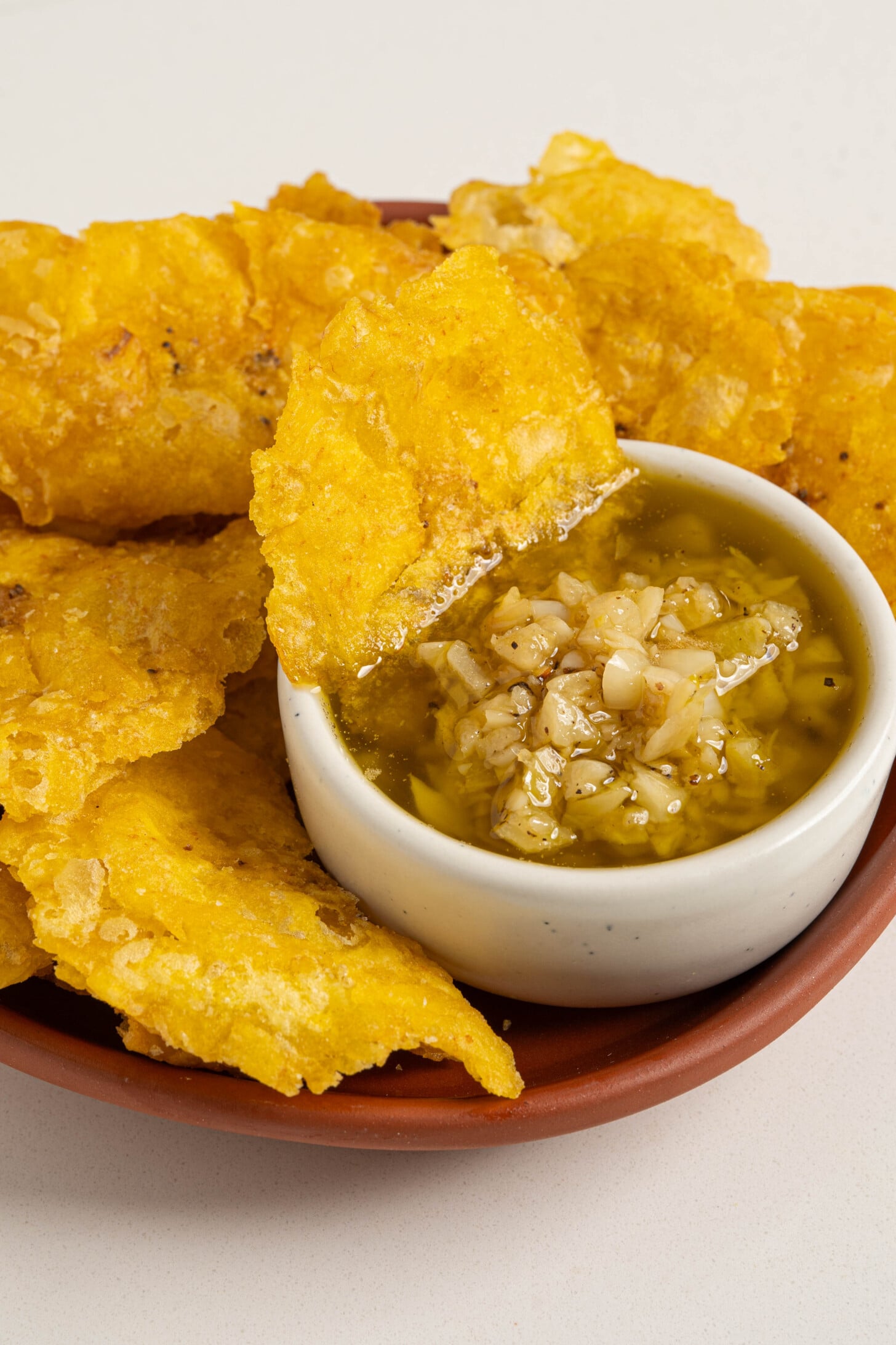 A bowl of mojo sauce with plantains.