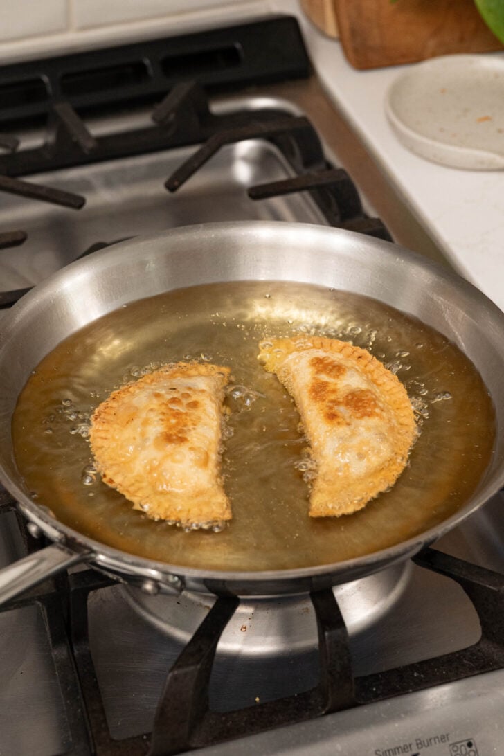 Beef empanadas frying in oil.