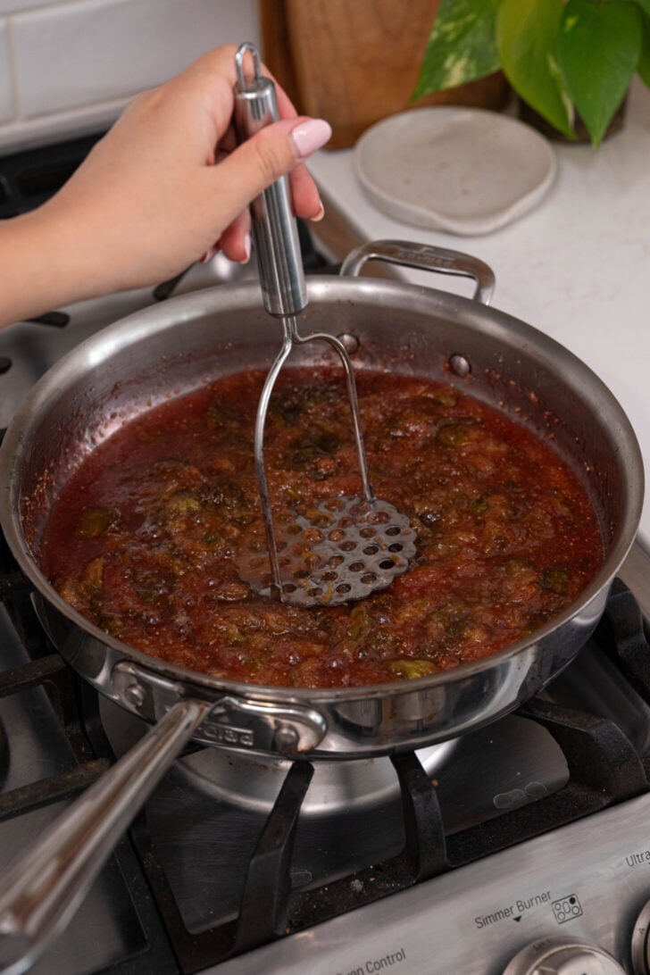Fig jam being mashed in a pan.
