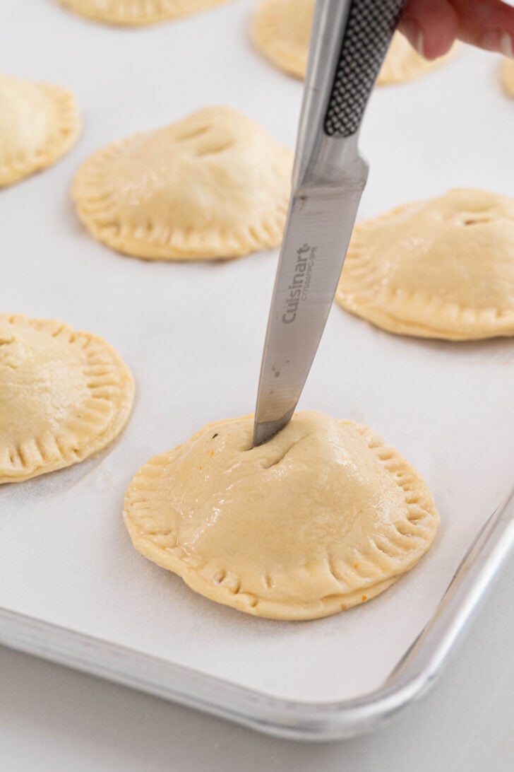 Pastelitos de carne being vented with a knife.