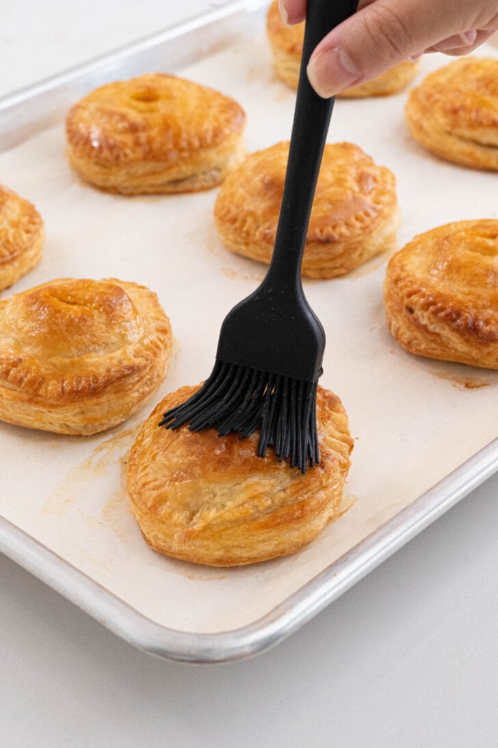 Pastelitos de carne being brushed with simple syrup.