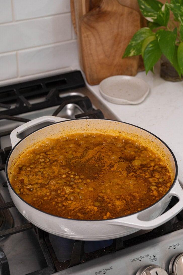 Gandules, spices, broth, and rice in a pot.