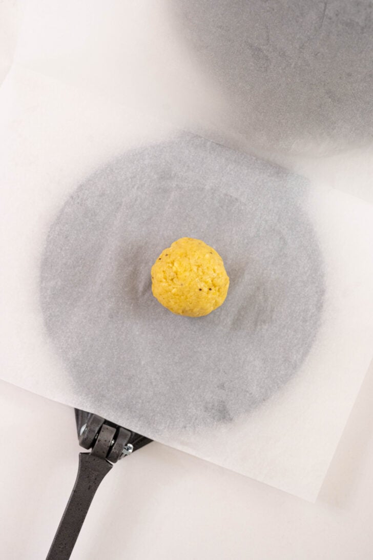 A ball of plantain dough in a tortilla press.