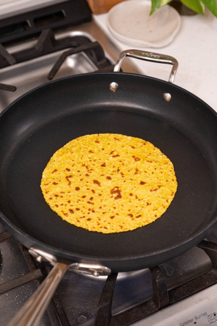A plantain tortilla toasting in a pan.